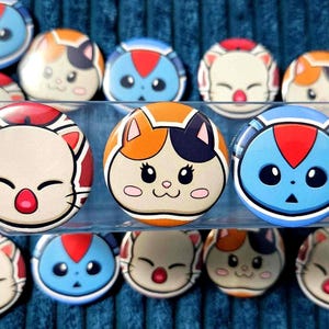 May include: A collection of round, colorful cat-faced buttons. The buttons feature various designs with red, orange, blue, and white accents. The cat faces have different expressions, with closed eyes and smiling faces.