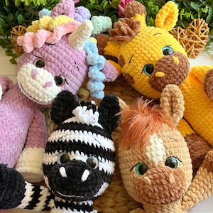 May include: A collection of handmade crochet animal plushies, including a purple unicorn with a rainbow mane, a yellow giraffe, a black and white zebra, and a brown horse with an orange mane. Each plushie has large, expressive eyes.