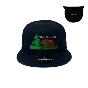 May include: A black and green embroidered baseball cap with the words "CALIFORNIA" and a bear with a heart on its chest. The cap is made by "DECKY ORIGINAL".