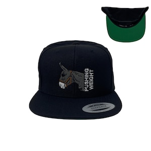 May include: A black and green baseball cap with an embroidered image of a donkey and the text "PUSHING WEIGHT".