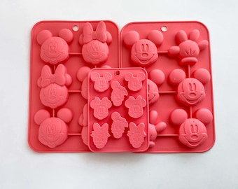 May include: Three pink silicone baking molds with different Disney character designs. The molds are for making chocolate or candy. The first mold has Mickey Mouse, Minnie Mouse, and Donald Duck designs. The second mold has Mickey Mouse, Minnie Mouse, and Goofy designs. The third mold has Mickey Mouse, Minnie Mouse, and Pluto designs.