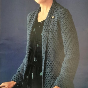 May include: A teal blue crocheted cardigan with a loose fit and open front. The cardigan is made with a lacy stitch pattern and has long sleeves.