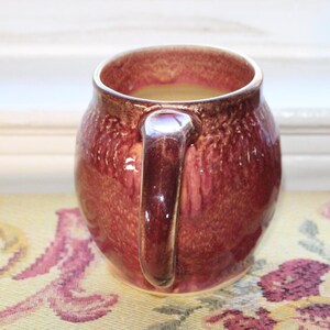 May include: Two ceramic mugs with a speckled, reddish-brown glaze. The mugs have a rounded body and a handle.
