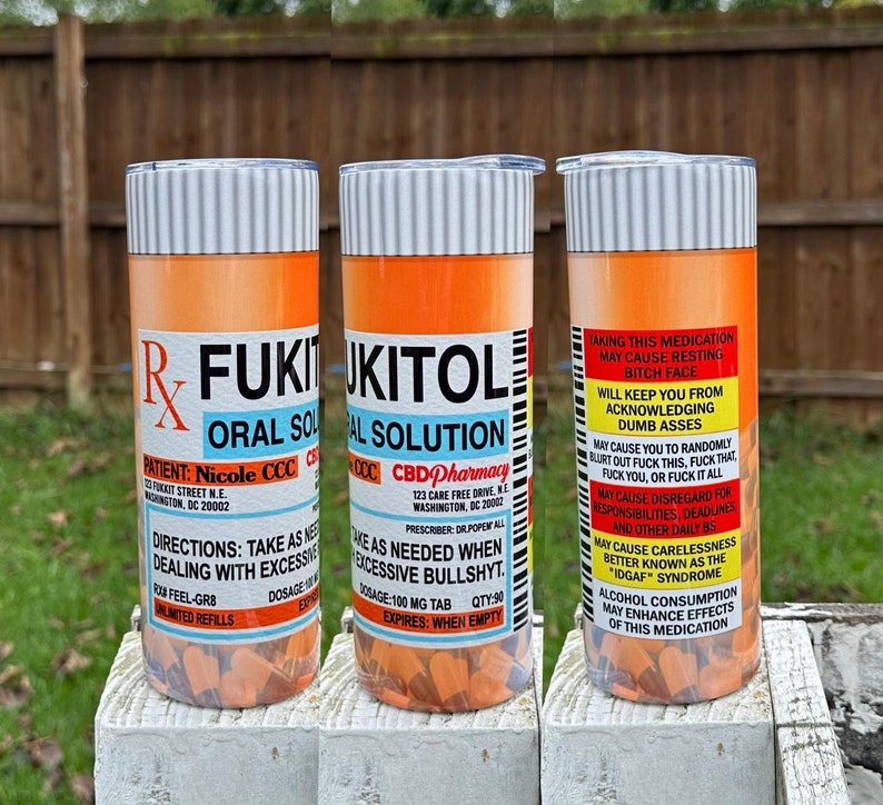 May include: Three orange and white pill bottle-shaped tumblers with the text "FUKITOL ORAL SOLUTION" and "CBD Pharmacy" on them. The tumblers are filled with orange pills.