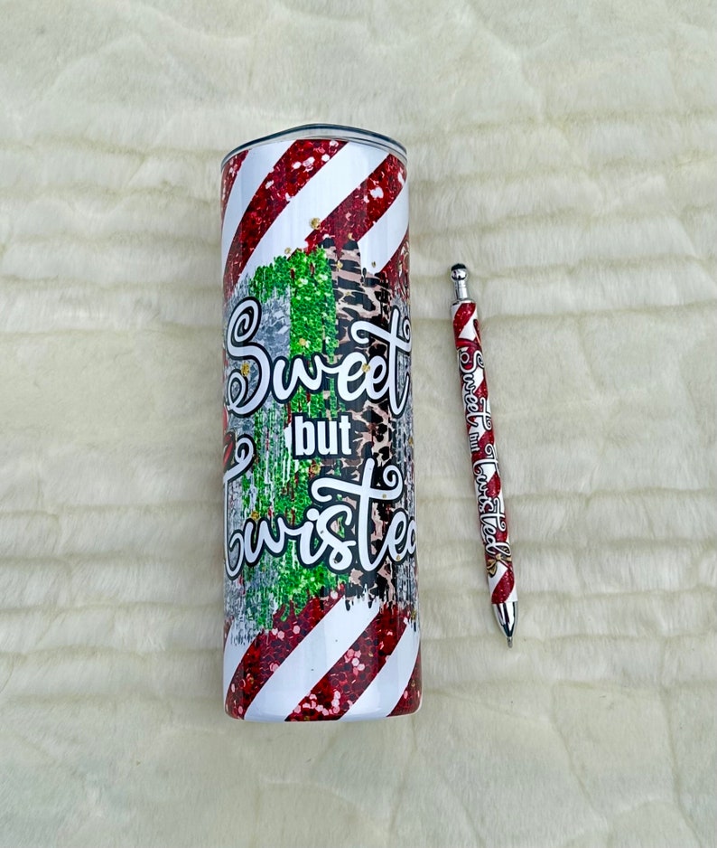 May include: A stainless steel tumbler and pen set. The tumbler features a red and white striped design with glitter accents and the words "Sweet but Twisted." The pen has a matching design.