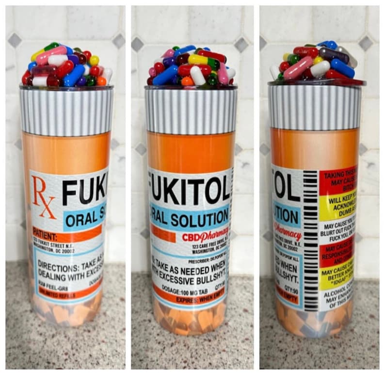 May include: A tall orange and white pill bottle with the text "R-FUKITOL ORAL SOLUTION" and "CBD Pharmacy" printed on it. The bottle is filled with colorful capsules and pills.
