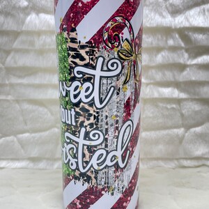 May include: A stainless steel tumbler with a candy cane design. The tumbler features red glitter stripes, white stripes, and the text "Sweet but Twisted". The design includes a candy cane and a gold bow.