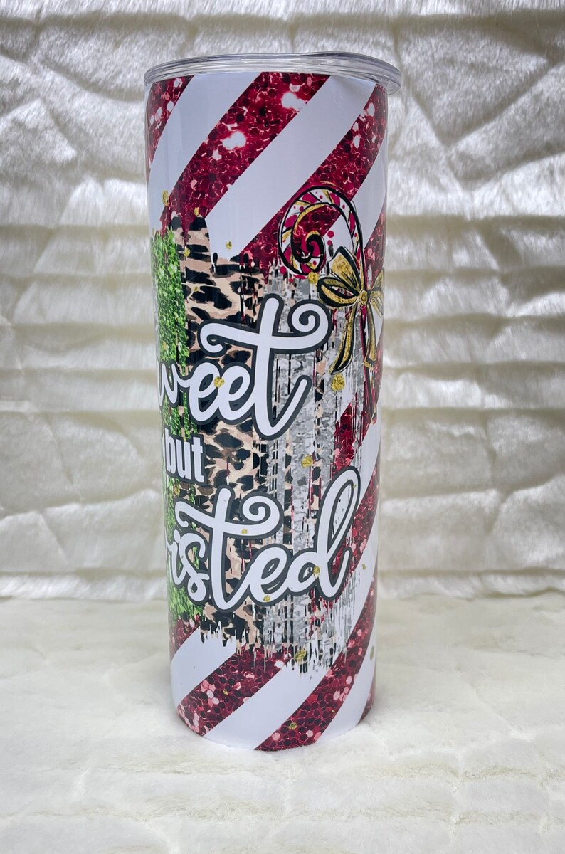 May include: A stainless steel tumbler with a candy cane design. The tumbler features red glitter stripes, white stripes, and the text "Sweet but Twisted". The design includes a candy cane and a gold bow.