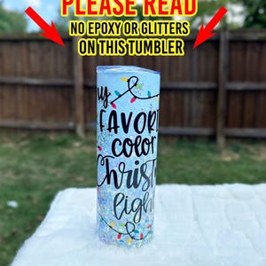 May include: A blue tumbler with glitter and a white design that says "My favorite color Christmas lights".