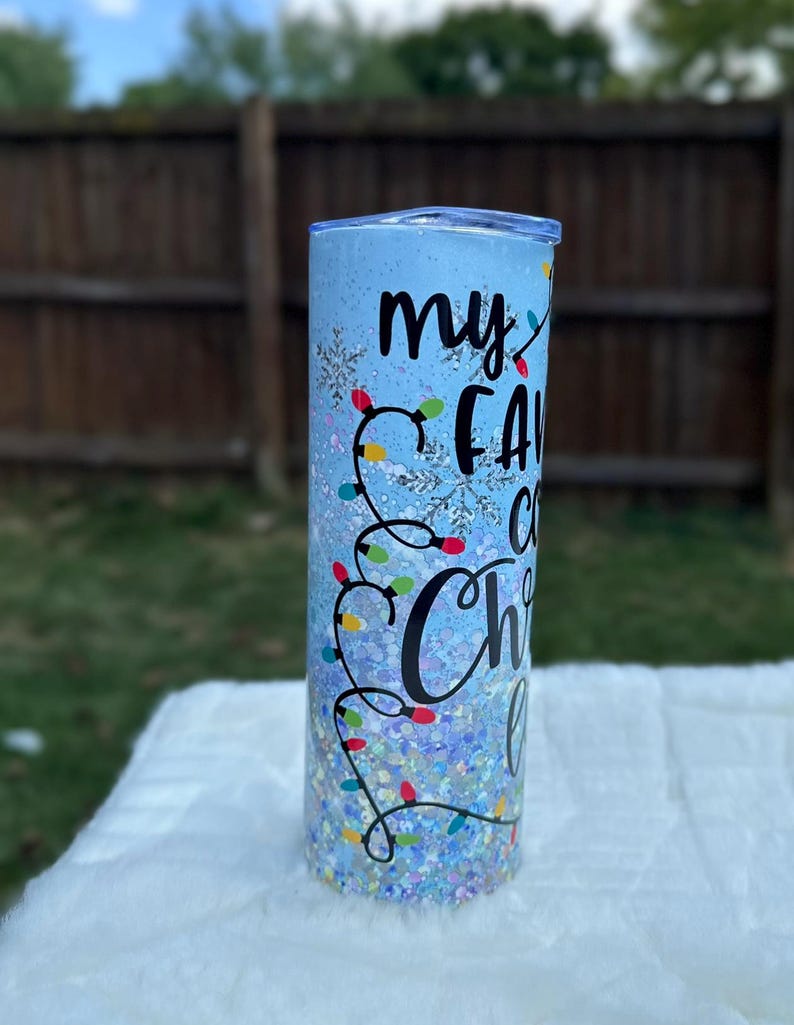 May include: A blue glitter tumbler with a white snowflake design and the text "my favorite Christmas lights" in black.