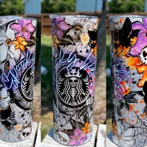 May include: A tall, stainless steel tumbler with a Halloween-themed design. The design includes purple and orange flowers, spiderwebs, bats, and a skull. The Starbucks logo is visible, with a skeleton in place of the usual figure. The word "Spooky" is written in cursive.