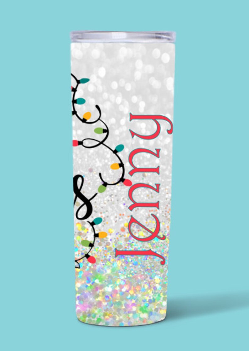 May include: A white tumbler with a silver glitter finish and a design of colorful Christmas lights and the name "Jenny" in red.