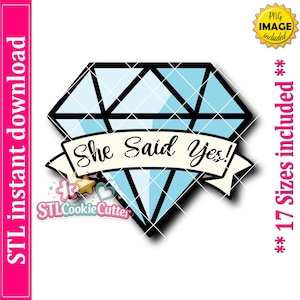 May include: A light blue diamond-shaped graphic with a black outline and a white banner across the center featuring the black text She Said Yes!. The design includes a small logo with a star and heart icon and the text STLCookieCutter.