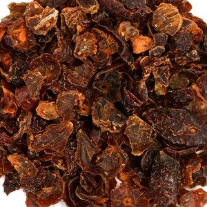 May include: A close-up of a pile of dried rose hips. The rose hips are a deep reddish-brown color and have a slightly wrinkled texture.