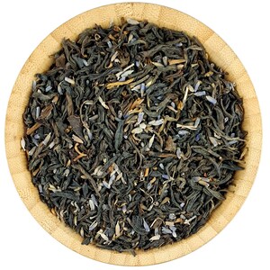 May include: A close-up of a wooden bowl filled with loose leaf black tea blended with lavender buds. The tea is a dark green color with purple lavender buds throughout.
