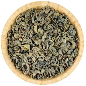 May include: A close-up view of a bowl of loose leaf green tea. The tea leaves are a dark green colour and are curled into small balls.