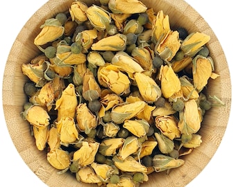 May include: A wooden bowl filled with dried yellow rose buds and green tea leaves. The rose buds are a pale yellow colour and the tea leaves are a dark green colour.