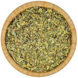 Könnte beinhalten: Eine Holzschale gefüllt mit getrockneten grünen Kräutern. Die Kräuter sind fein gehackt und haben eine hellgrüne Farbe.