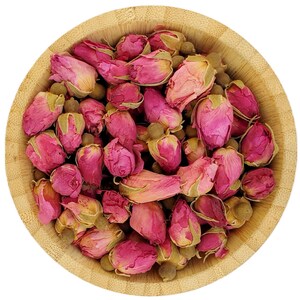 Op de afbeelding: Een houten kom gevuld met gedroogde roze rozenknoppen. De knoppen zijn lichtroze van kleur en zijn willekeurig gerangschikt. De kom is gemaakt van lichtbruin hout en heeft een gladde afwerking.