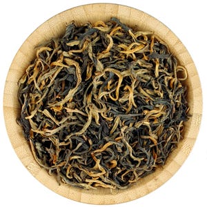 Puede incluir: Primer plano de té negro en hojas sueltas con puntas doradas en un cuenco de madera. El té es una mezcla de hojas de té negro y puntas doradas.