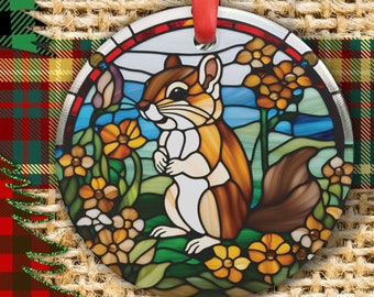 May include: A stained glass ornament featuring a brown and white squirrel with a bushy tail, surrounded by yellow flowers and green leaves. The ornament is round and has a red ribbon attached.