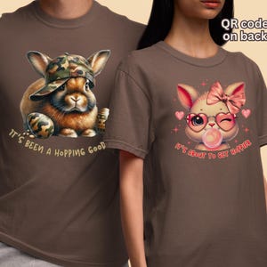 May include: Two brown t-shirts with bunny rabbit illustrations. The first shirt features a brown bunny with a camouflage hat and the text "It's been a hopping good". The second shirt features a pink bunny with a pink bow and the text "It's about to get hoppier".