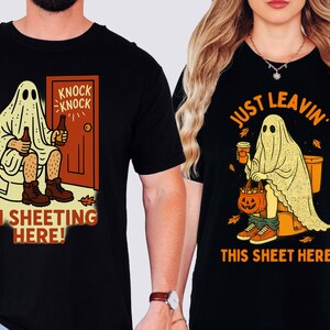 May include: Black t-shirts with Halloween-themed graphics. One shirt features a ghost on a toilet with the text "I'M SHEETing HERE!". The other shirt shows a ghost with a coffee cup and a pumpkin basket, with the text "JUST LEAVIN' THIS SHEET HERE."