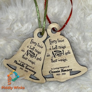 May include: Two wooden bell ornaments with the text "Every time a bell rings an Angel gets their wings."  The first ornament has the text "In Loving Memory of Paulette Sweeney 1953-2021". The second ornament has the text "In Loving Memory of Connie Henson 1950-2021".
