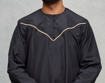 Puede incluir: Una camisa negra de manga larga con un diseño bordado en dorado en el cuello. La camisa tiene un cuello abotonado.