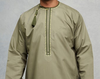 Puede incluir: Un hombre vistiendo una camisa de manga larga de color verde oliva con cierre de cremallera y ribetes dorados. La camisa tiene un detalle de borla en el cuello.