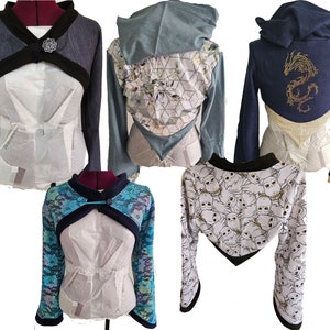 May include: Four cropped images of long-sleeved, cropped sweaters with various patterns. The first sweater is black and grey with a black collar and a gold button. The second sweater is blue and white with a floral pattern and a hood. The third sweater is navy blue with a gold dragon design. The fourth sweater is white with a black and white owl pattern.