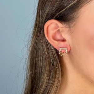 Peut inclure: Boucles d'oreilles en or avec trois cercles entrelacés, chacun avec une rangée de petites pierres roses.