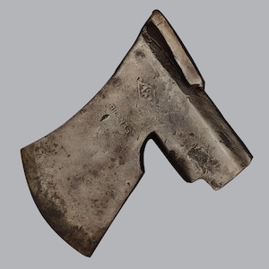 Op de afbeelding: Een verweerde stalen bijlkop met een donkere, gevlekte patina. Het metalen oppervlak is voorzien van de gestempelde tekst "BILNAS" en een ruitvormig logo. Het gereedschap heeft een gebogen snijvlak en een rechthoekig oog voor een steel.