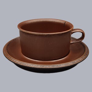 Puede incluir: Un juego de taza y platillo de cerámica marrón. La taza tiene una forma redondeada con un asa, y el platillo es circular. El juego tiene un acabado mate y un diseño simple y clásico. Perfecto para disfrutar del café o té.