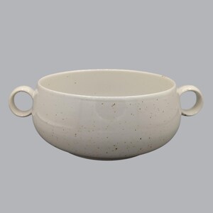 Peut inclure: Un bol à soupe en céramique de couleur crème présentant un motif moucheté sur toute sa surface intérieure et extérieure. Le bol est conçu avec deux anses circulaires sur les côtés opposés, offrant une prise équilibrée pour servir.