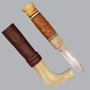 May include: A fixed-blade knife with a metallic blade and a handle crafted from light-colored bone and textured brown wood, accented with thin black rings. Beside it lies a brown leather sheath featuring a curved, light-colored bone base.