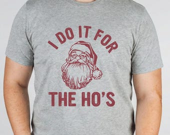 May include: Grey athletic heather t-shirt featuring the burgundy text "I DO IT FOR THE HO'S" and a Santa Claus graphic. The t-shirt is made of a soft material and is suitable for casual wear.