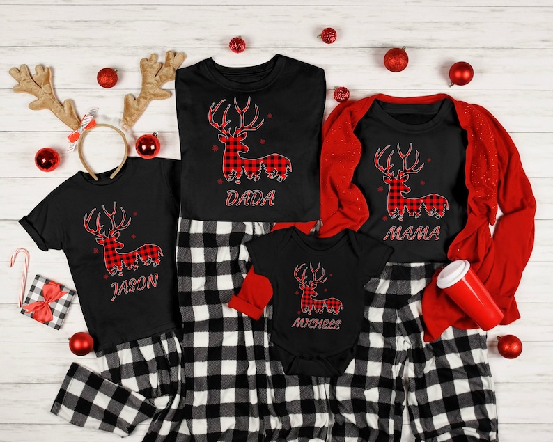 Puede incluir: Un conjunto de pijamas navide&ntilde;os a juego para la familia con un estampado de cuadros rojos y negros. Las camisas presentan un reno de cuadros rojos y negros con las palabras "Dada", "Mama", "Jason" y "Michael" impresas en cada camisa.
