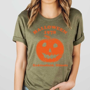 May include: A green t-shirt with an orange pumpkin graphic and the text "Halloween 1978 Haddonfield, Illinois".