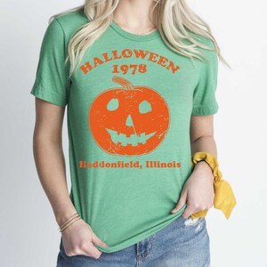 May include: Green t-shirt with a vintage-style orange pumpkin graphic and the text "HALLOWEEN 1978 Haddonfield, Illinois".
