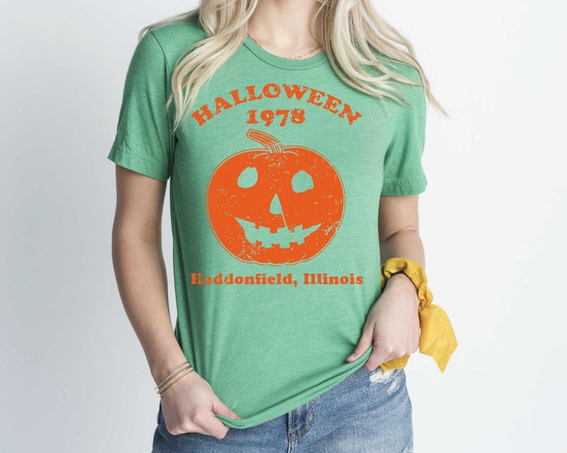 May include: Green t-shirt with a vintage-style orange pumpkin graphic and the text "HALLOWEEN 1978 Haddonfield, Illinois".