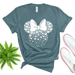 Może przedstawiać: Koszulka w kolorze turkusowym z białą sylwetką głowy Minnie Mouse wykonaną z serc.