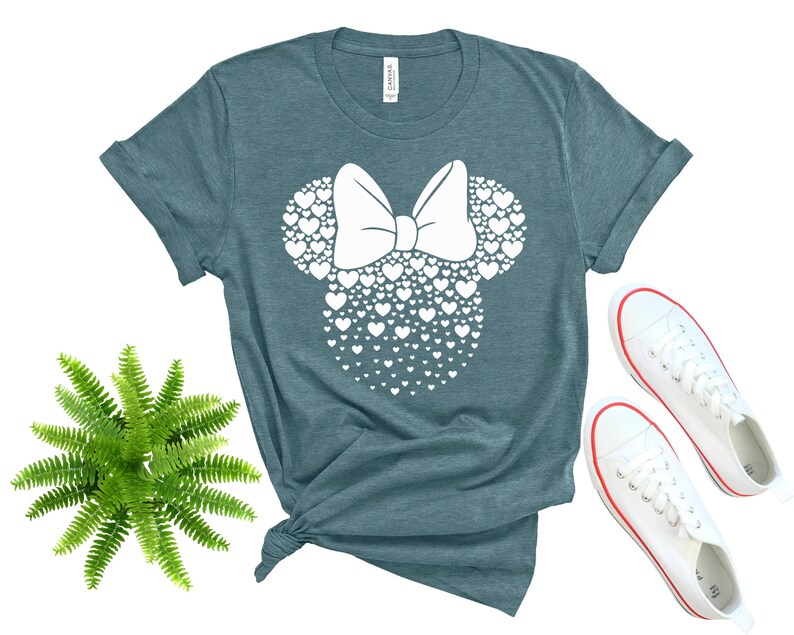 Może przedstawiać: Koszulka w kolorze turkusowym z białą sylwetką głowy Minnie Mouse wykonaną z serc.