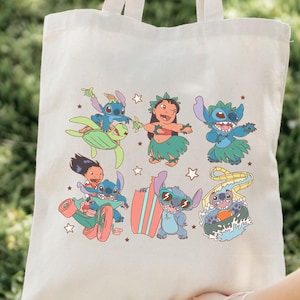 May include: A white canvas tote bag with a colorful print of Stitch from Lilo & Stitch. The print features Stitch in various activities, including surfing, riding a scooter, and hula dancing. The bag has two handles and is perfect for carrying everyday essentials.