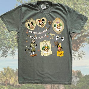 May include: A green t-shirt with a print of various Disney characters from Animal Kingdom. The characters include Mickey Mouse, Minnie Mouse, Donald Duck, Goofy, and Pluto. The print also includes the words "Animal Kingdom" in a banner.