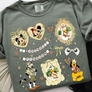 May include: A green t-shirt with a print of various Disney characters in an animal kingdom theme. The characters include Mickey Mouse, Minnie Mouse, Donald Duck, Goofy, and Pluto. The text "Animal Kingdom" is printed on the shirt.