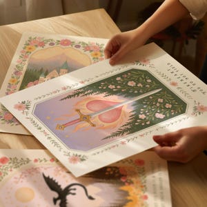 May include: Art prints with floral borders and fantasy illustrations. One print shows a sword piercing a heart in flames, with the text "FIRE HEART YOU DO NOT YIELD." Another depicts a castle. The prints are being held by a person.