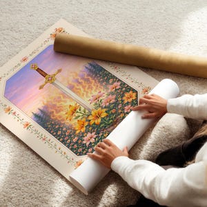 May include: A rolled-up art print featuring a fantasy scene with a sword, flowers, and a sunset. The print is being unrolled, revealing a detailed illustration with a floral border. A brown paper tube is also visible.