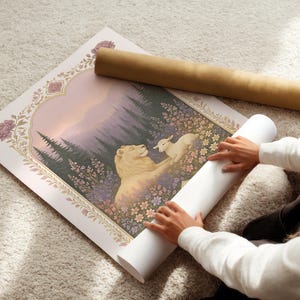 May include: A rolled art print featuring a lion and lamb in a field of flowers, with a forest backdrop. The print is framed with floral and arch details. A brown cardboard tube and a white rolled print are next to the artwork.