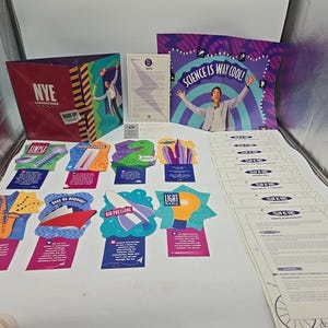 May include: A collection of educational materials, including a red box labeled "NYE Laboratories" and cards with science-related illustrations and text. A poster reads "Science is Way Cool!" with a person raising their arms.